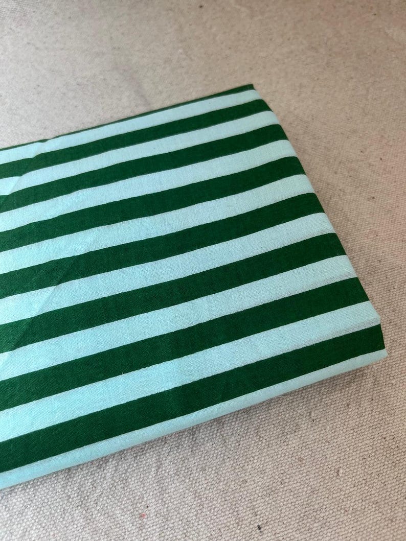 "Draped Carnival Cotton fabric, showcasing its lightweight structure and elegant drape. Ideal for sewing modern fashion projects, transitional seasonal wear, and home décor accents. The woven texture ensures breathability and comfort."
