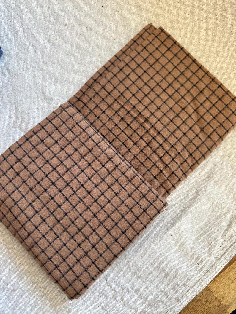 Fabric rolled loosely on a cutting mat, ready for DIY cutting and patterning. Brushed cotton grid plaid fabric features a soft, cozy feel and woven plaid details. Perfect for a wide range of projects including baby blankets, clothing, and decorative pieces. The photo captures the tactile quality and versatility of this textile.