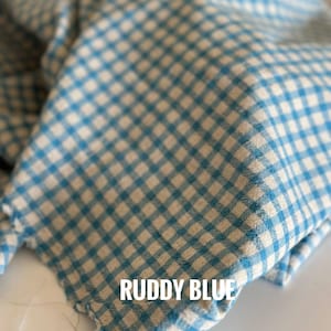 "Rolled gingham linen-cotton blend fabric, showcasing its lightweight, eco-friendly composition. Ideal for sewing summer outfits, aprons, and upholstery projects. The breathable weave enhances airflow, ensuring a cool and comfortable feel for everyday wear."