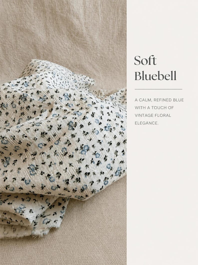 May include: A white fabric featuring a small-scale blue and black floral pattern with a textured weave. The text on the right side reads: Soft Bluebell, A CALM, REFINED BLUE WITH A TOUCH OF VINTAGE FLORAL ELEGANCE.