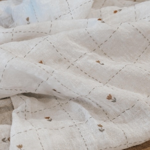 Soft Salt Air cotton gauze fabric displayed in natural light, highlighting its airy, breathable weave and lightly crinkled texture. This lightweight double gauze cotton drapes beautifully with a relaxed, coastal-inspired feel. Shown folded to emphasize softness and movement, this fabric is ideal for baby blankets, swaddles, summer dresses, and layering garments. The neutral tone and organic texture make it perfect for modern sewing projects and everyday wearable pieces.