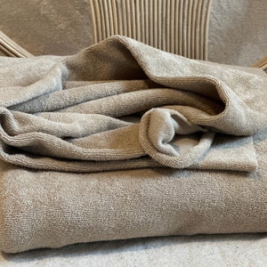 "Folded organic cotton sponge knit terry fabric, highlighting its thick, absorbent loops and natural cotton fibers. Ideal for creating sweatshirts, hoodies, and eco-conscious fashion pieces. The soft, organic cotton ensures a gentle touch on the skin, making it suitable for sensitive skin and baby clothing."