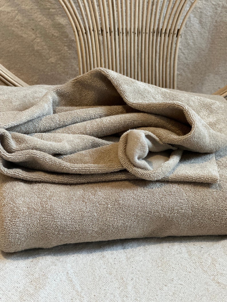 "Folded organic cotton sponge knit terry fabric, highlighting its thick, absorbent loops and natural cotton fibers. Ideal for creating sweatshirts, hoodies, and eco-conscious fashion pieces. The soft, organic cotton ensures a gentle touch on the skin, making it suitable for sensitive skin and baby clothing."