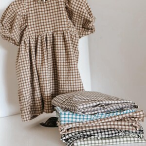 "Draped gingham linen-cotton blend fabric, showcasing its woven texture and airy feel. Great for sewing dresses, shirts, curtains, and table linens. The natural fibers ensure breathability and comfort, making it a sustainable choice for fashion and home projects."