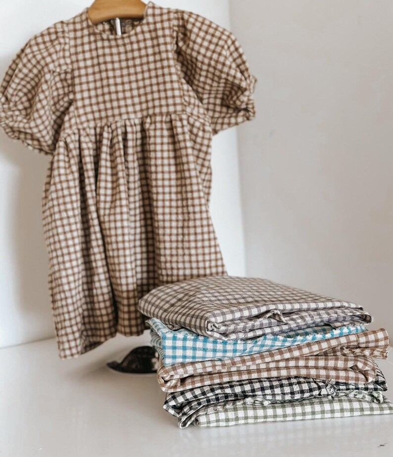 "Draped gingham linen-cotton blend fabric, showcasing its woven texture and airy feel. Great for sewing dresses, shirts, curtains, and table linens. The natural fibers ensure breathability and comfort, making it a sustainable choice for fashion and home projects."
