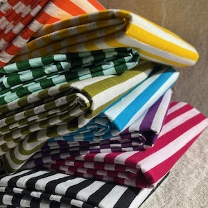 "Draped Carnival Cotton fabric, highlighting its smooth, tightly woven texture and festive patterns. Great for sewing stylish apparel, lightweight curtains, and decorative accents. The natural cotton fibers enhance breathability, ensuring a comfortable feel."