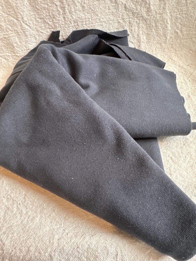 Image showing folded 1x1 cotton rib knit fabric to highlight flexibility and natural drape. The photo focuses on the ribbed texture, breathable cotton fibers, and soft matte surface. Proudly milled in the USA, this 100% cotton rib knit is ideal for sewing tops, trims, and cuffs. The detailed image emphasizes quality construction, tight weave, and stretch structure that enhances comfort and durability for handmade apparel.