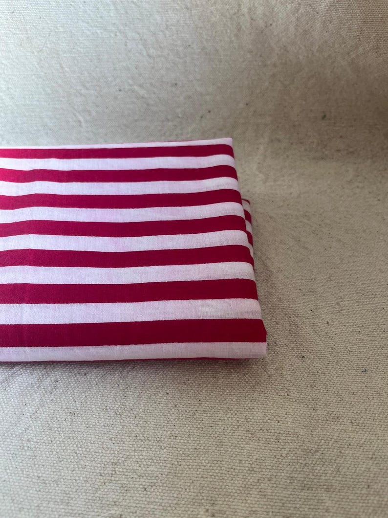 "Folded Carnival Cotton fabric, emphasizing its crisp texture and semi-opaque finish. Perfect for creating tailored dresses, structured skirts, and stylish tops. The handcrafted prints add a unique touch, making it ideal for artisan sewing projects."