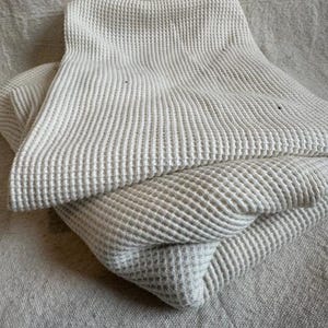 Close-up view of premium heavyweight cotton waffle knit fabric featuring a raised waffle texture. This durable cotton knit is perfect for thermal tops, sweatshirts, pullovers, robes, and blanket sewing projects. The fabric has a cozy feel with excellent structure while remaining breathable and comfortable against the skin. Ideal for makers looking for a high-quality waffle knit fabric sold by the half yard for garment and home sewing.