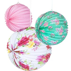 May include: Three round paper lanterns with floral patterns. The lanterns are pink, green, and white with a white background and colorful floral designs.