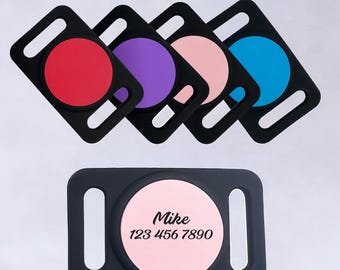 May include: A collection of black pet tag holders with colored circular inserts in red, purple, pink, and blue. A separate tag shows a pink circle with the name "Mike" and a phone number.