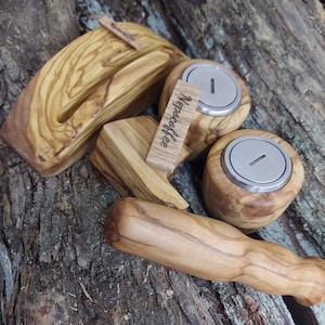 Puede incluir: Una colección de accesorios de café de madera hechos a mano, que incluyen un soporte para teléfono, prensadores y portafiltros para máquinas de espresso. Los artículos son de madera marrón claro con vetas visibles y el texto "Nepcoffee".