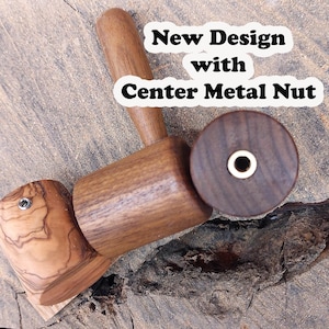 Peut inclure: Un maillet en bois avec un manche en bois brun et une tête en bois brun. La tête a un écrou métallique au centre. Le maillet est posé sur une surface en bois. "New Design with Center Metal Nut" est écrit en blanc sur fond noir.