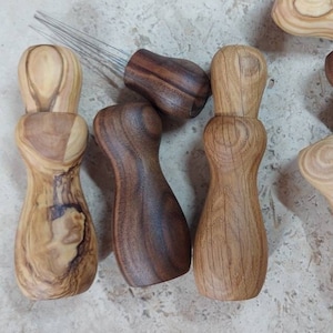 May include: Six wooden knitting needle holders with different wood grain patterns. The holders are shaped like small, slender bottles with a rounded top and a narrow neck. Each holder has a set of metal knitting needles inserted into the top.