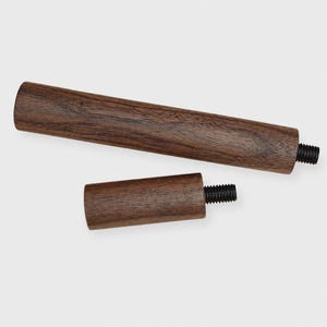 Peut inclure: Deux poignées cylindriques en bois brun foncé avec des motifs de grain visibles. Chaque poignée comporte un boulon métallique fileté noir dépassant d'une extrémité, conçu pour être fixé à une surface. Le bois a une finition mate lisse.