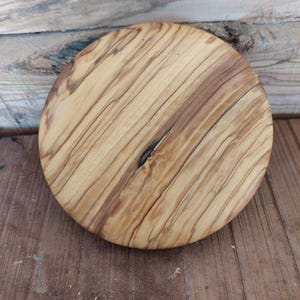 以下が含まれることがあります： 自然な木目模様の丸い木製まな板。板は薄い茶色の木でできており、濃い茶色の筋が入っています。