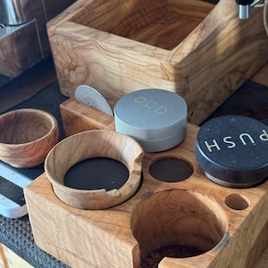May include: A wooden coffee station with a gray metal container labeled "OCD", a black container labeled "PUSH", and a wooden bowl. The station has multiple compartments for holding coffee accessories.