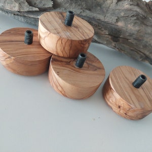 May include: Four wooden round bases with a metal screw in the centre. The bases are made of light brown wood with a natural grain pattern.