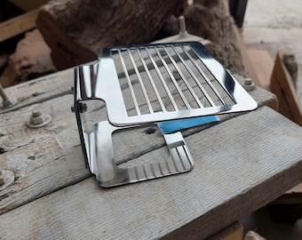 Pode incluir: Uma grelha de radiador de motocicleta cromada com forma retangular e um padrão de grade. A grelha é feita de metal e tem um acabamento brilhante.
