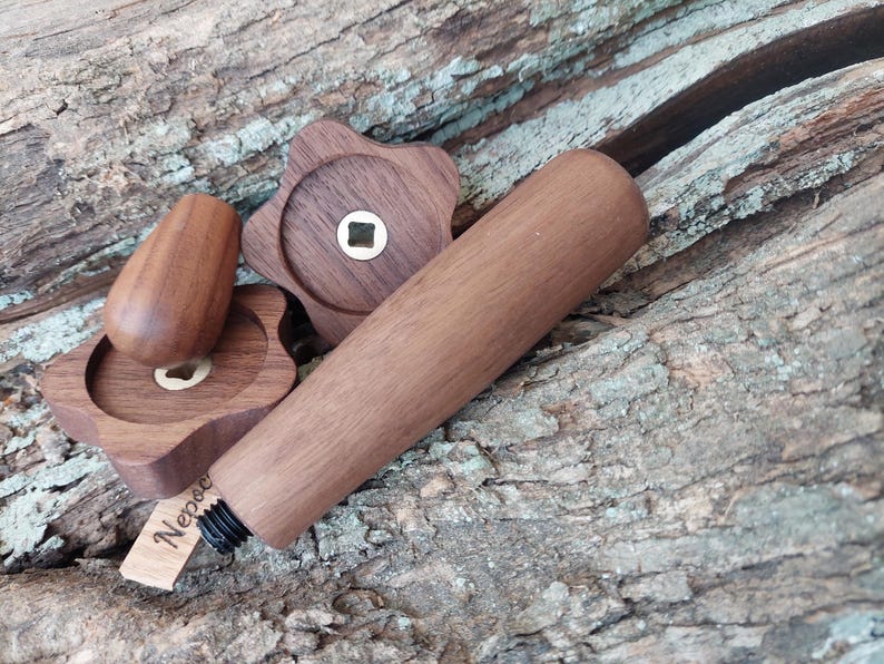 May include: A set of wooden bottle stoppers, featuring a star-shaped design and a cylindrical handle. The set includes a stopper, two star-shaped pieces, and a cylindrical piece. The wood is a warm brown colour, and the set is on a textured wooden surface.