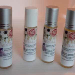May include: Four silver roll-on bottles with white labels and floral designs. The labels read "Natural Aromatherapy Essential Oil Blend" and list the blend's name.