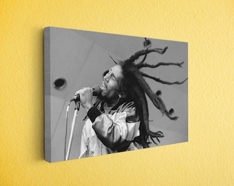 May include: Black and white canvas print of a man singing into a microphone. The man has long dreadlocks and is wearing a jacket. The image is mounted on a canvas and displayed on a yellow wall.