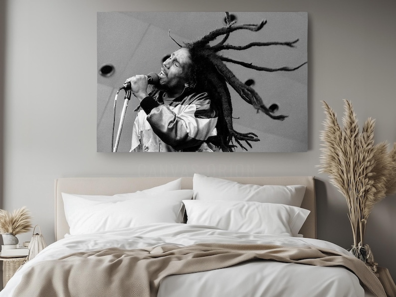 a bed with a white comforter and a picture of a man with dreadlock