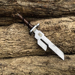 May include: A metal dagger with a textured, silver-toned blade featuring a distinct cutout notch near the hilt. The handle is wrapped in dark brown leather with black cord lacing. A small rectangular metal plate is embedded on the blade surface.