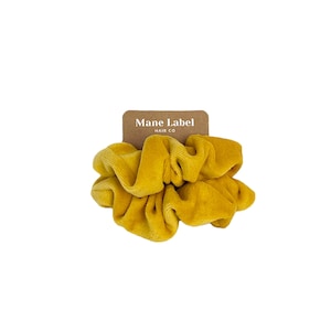 May include: A yellow velvet scrunchie with a brown tag that reads 'Mane Label Hair Co.'