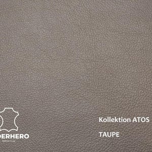May include: Close-up of taupe-colored leather with a textured surface. The image includes the text "Kollektion ATOS" and "TAUPE". The "LEDERHERO" logo is also visible. This leather is suitable for various crafting projects.