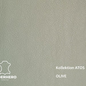 May include: A close-up of a light green leather swatch with the text "Kollektion ATOS OLIVE" printed on it. The leather has a textured surface.