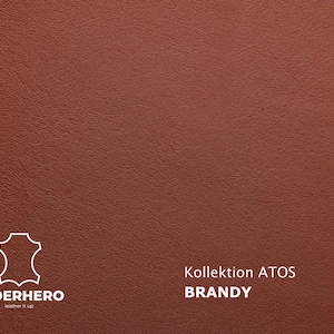 May include: Close-up of a textured, reddish-brown leather surface. The image includes the text "Kollektion ATOS BRANDY" and a logo for LEDERHERO, a leather goods company.