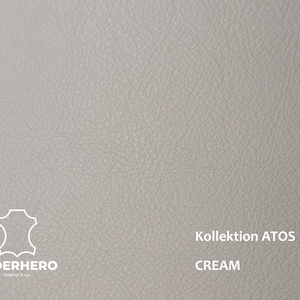 May include: Close-up of a light grey leather swatch with a textured surface. The swatch has the text "Kollektion ATOS CREAM" printed on it.