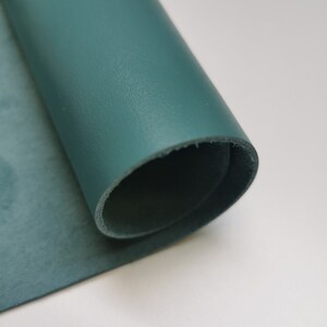 May include: A roll of teal leather, showing the smooth, textured surface on one side and the suede-like texture on the other side.