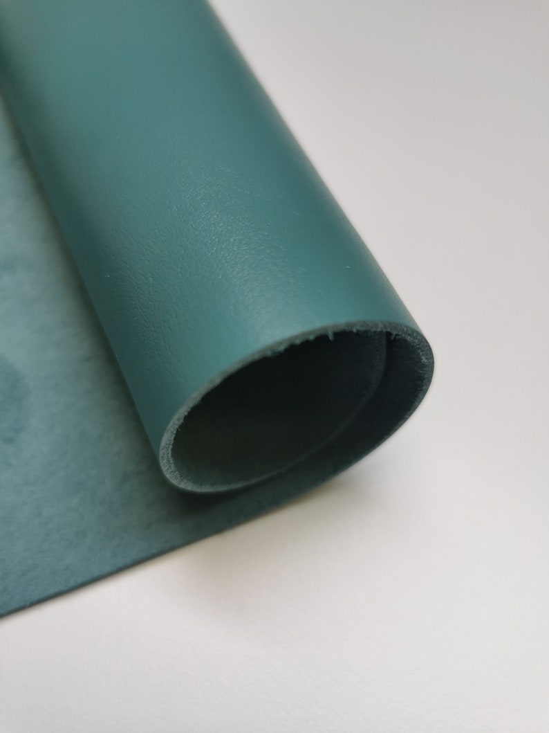 May include: A roll of teal leather, showing the smooth, textured surface on one side and the suede-like texture on the other side.