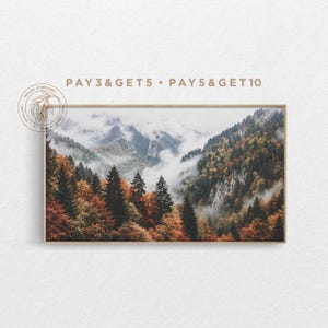 Puede incluir: Una impresión de paisaje enmarcada que muestra una cadena montañosa cubierta de un bosque denso con follaje otoñal en tonos naranja, amarillo y verde, parcialmente oculta por nubes blancas bajas. El texto PAY 3 & GET 5 • PAY 5 & GET 10 es visible.