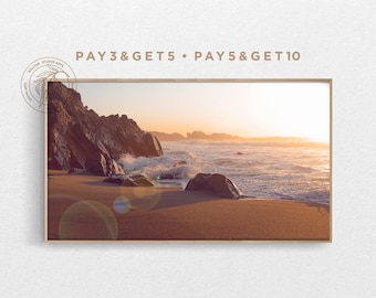 Könnte beinhalten: Ein gerahmtes Foto eines felsigen Strandes mit Wellen, die bei Sonnenuntergang an das Ufer krachen. Der Himmel ist in sanftem Orange und Rosa gehalten, das Wasser ist tiefblau. Der Text "PAY 3 & GET 5 • PAY 5 & GET 10" ist oben im Bild gedruckt.