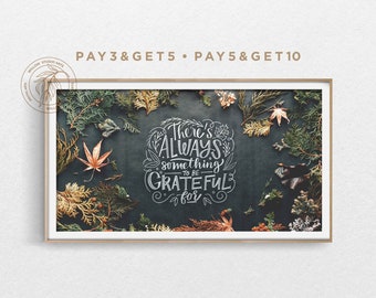 May include: A framed print featuring the words "There's ALWAYS something to be GRATEFUL for" in white script. The artwork is surrounded by autumn leaves and greenery on a dark background. The frame is a light brown colour.