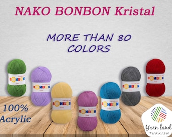 May include: A selection of Nako Bonbon Kristal yarn colours, a 100% acrylic yarn. The yarn is shown on a wooden surface. The text "More than 80 colours" is displayed above the yarn. The text "100% Acrylic" is displayed below the yarn. The text "Yarn land TURKISH" is displayed in the bottom right corner of the image.