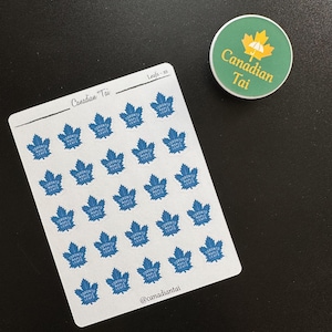 Op de afbeelding: Een wit stickervel met vijfentwintig kleine blauwe Toronto Maple Leafs-logo stickers, met de tekst Canadian Tai en Leafs-xs bovenaan en @canadiantai onderaan, naast een ronde groene sticker met een geel esdoornblad-icoon.