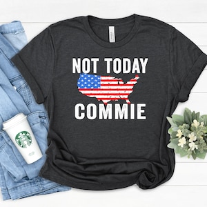 May include: A dark gray t-shirt with a distressed American flag design and the text "NOT TODAY COMMIE" printed on it.