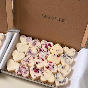May include: A box of heart-shaped soaps. The soaps are white with floral accents in shades of red, purple, and black. The box is brown and has the text "LINES STUDIO" printed on it.