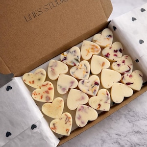 May include: A box of heart-shaped wax melts. Some melts are plain, while others are decorated with dried flower petals. The box is brown with the text "LINES STUDIO" printed on the lid. The melts are arranged on white paper.