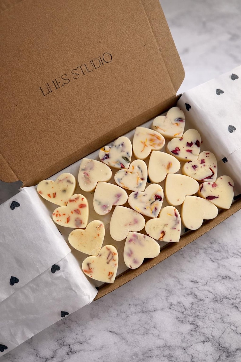 May include: A box of heart-shaped wax melts. Some melts are plain, while others are decorated with dried flower petals. The box is brown with the text "LINES STUDIO" printed on the lid. The melts are arranged on white paper.