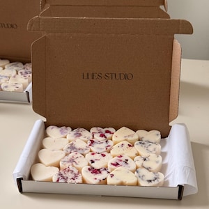 May include: A box of heart-shaped wax melts in a white tray. Some melts are plain, others are decorated with dried flowers. The box is inside a brown cardboard box with the text "LIHES STUDIO".