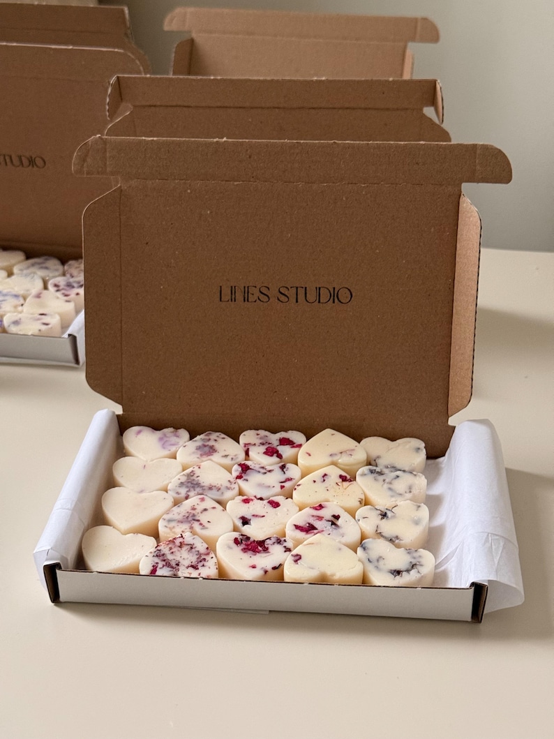 May include: A box of heart-shaped wax melts in a white tray. Some melts are plain, others are decorated with dried flowers. The box is inside a brown cardboard box with the text "LIHES STUDIO".