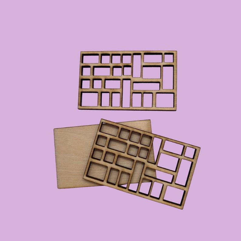 May include: Three wooden pieces with a geometric pattern cut out. The pieces are arranged in a stack, with the largest piece on the bottom and the smallest piece on top.