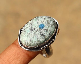 May include: A silver ring with a light blue and white oval gemstone. The gemstone has a speckled pattern and a small blue dot in the center.