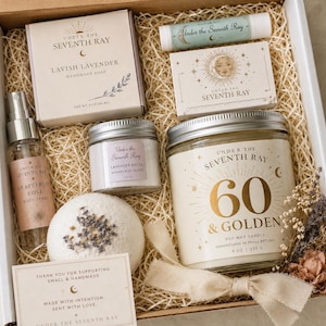 May include: A gift box containing a 9 oz soy wax candle labeled 60 & Golden, a 5 oz lavender soap bar, a 1.5 oz lavender body butter, a grapefruit rose body spray, a lip balm, a round bath bomb with dried flowers, and a small thank you card.