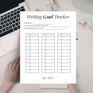 Op de afbeelding: Een wit Writing Goal Tracker-blad met zwarte tekst, inclusief secties voor maand, woordentelling en datums. De zin "You did it!" staat onderaan. Een laptop, koffiekopje en andere items staan op de achtergrond.